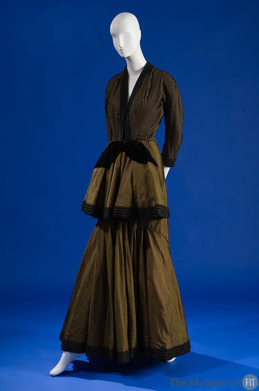 Green long sleeve floor length gown with black velvet and ribbon trim, front peplum with black …