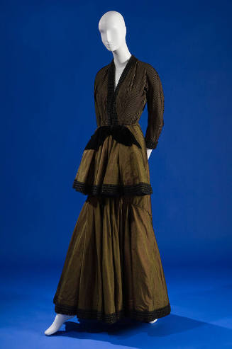 Green long sleeve floor length gown with black velvet and ribbon trim, front peplum with black …