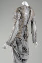 Back view of grey and beige tie back top beaded with tile design over grey knit dress with rust…