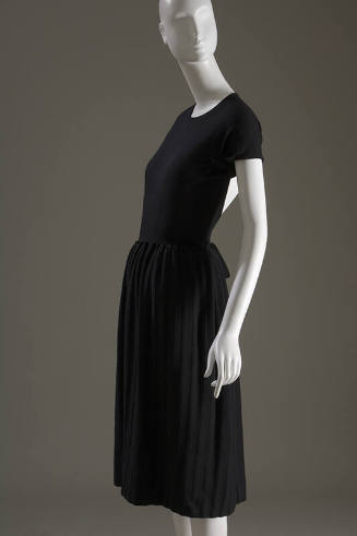 Side view of black short sleeve dress with vertical self fabric stripes on just below knee leng…