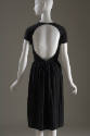 Back view of black short sleeve dress showing completely open back with single button back neck…
