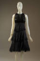 Black sleeveless dress with patent leather bodice and tired knee length skirt with fringed hems