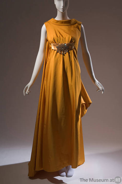 Orange sleeveless floor length evening gown with train, rolled high collar and large rhinestone…