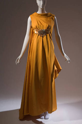 Orange sleeveless floor length evening gown with train, rolled high collar and large rhinestone…