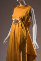 ¾ view of orange evening gown showing rolled collar extending to deep V-back and ending in over…