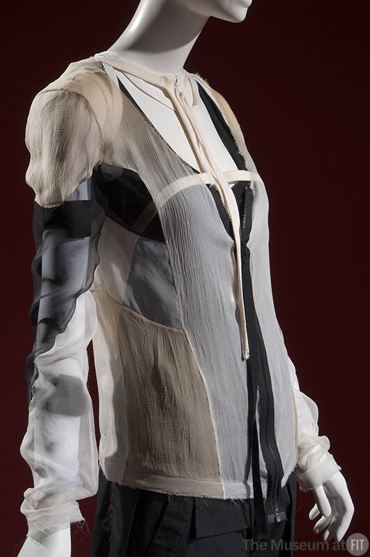¾ view of sheer beige, black and white irregular patchwork jacket with blank pants
