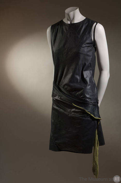 Black sleeveless mini dress with diagonal seaming and attached chartreuse panel at dropped wais…