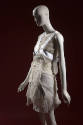 ¾ view of ensemble with grey sheer sleeveless cropped top, white pleated mini dress and white h…