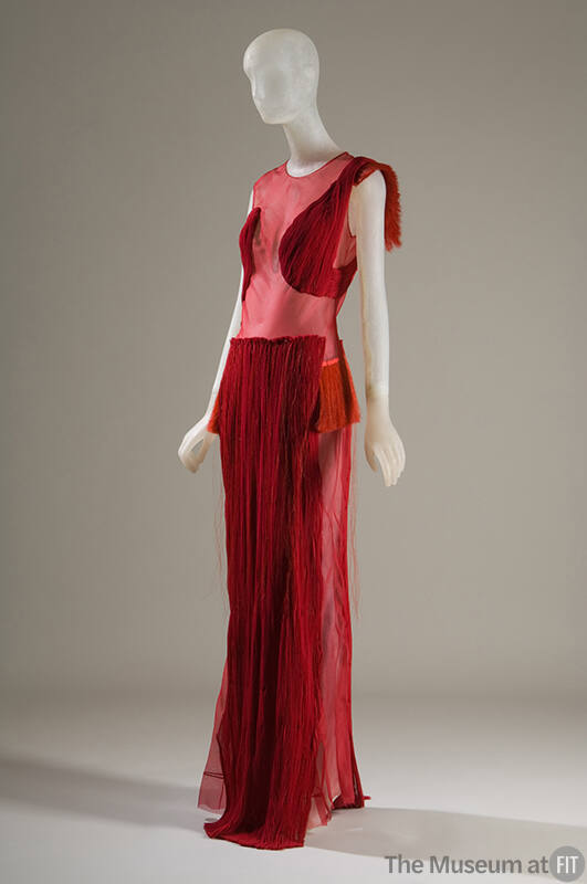 Red sleeveless floor length evening gown with sheer bodice and pleated appliques throughout and…