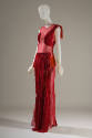 Red sleeveless floor length evening gown with sheer bodice and pleated appliques throughout and…