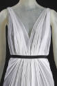 Detail view of white sleeveless gown bodice showing deep plunging V-neckline and ribbon belt at…