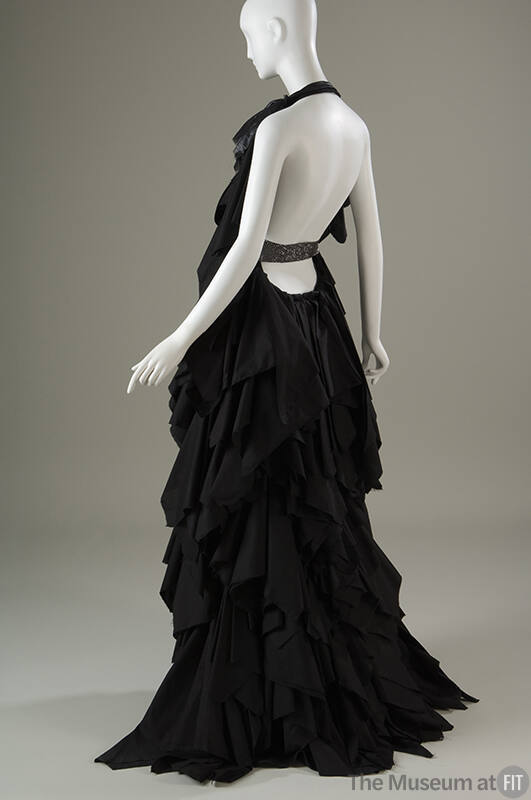 Back view of black floor length halter evening gown with open back and cotton and chiffon ruffl…