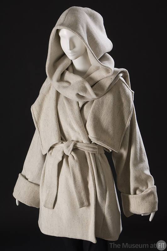 Off-white hooded  hip length wool coat with hanging front flaps, wide cuffed sleeves, sash belt