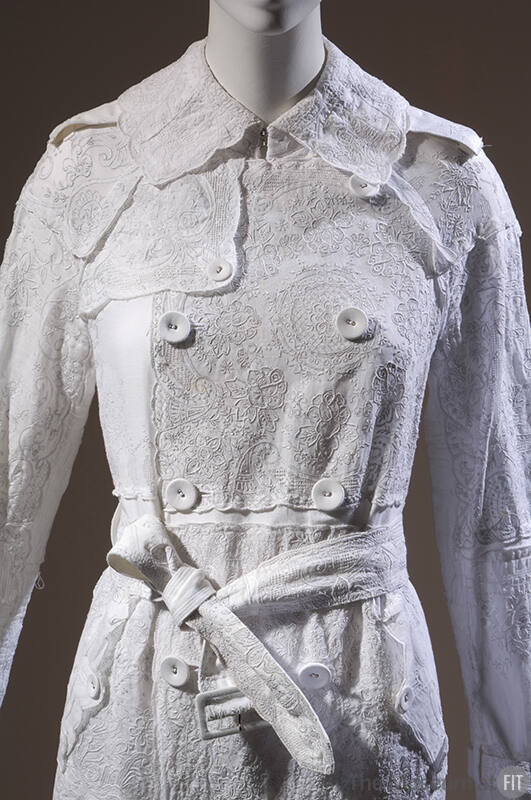 Detail of white embroidered cotton handkerchief double-breasted coat with belt 