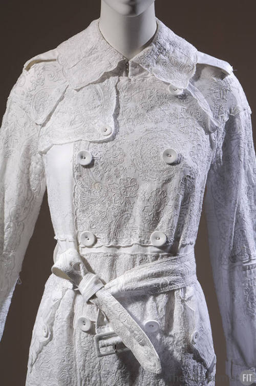 Detail of white embroidered cotton handkerchief double-breasted coat with belt 