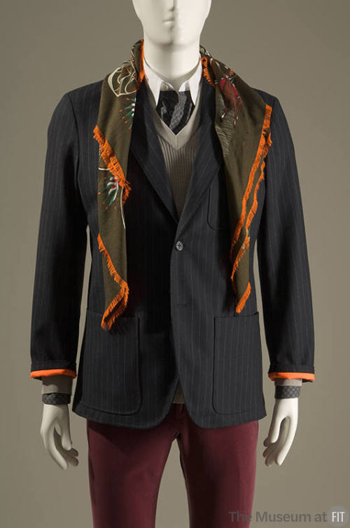 Navy blue pinstripe one button jacket with patch pockets, green silk scarf and red pants 