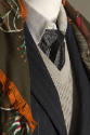 Detail of navy blue pinstripe jacket, grey knit vest over white collar shirt and green and oran…
