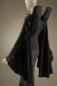 Back detail of black and grey jacket with double high stand collar and bat wing sleeves over a …