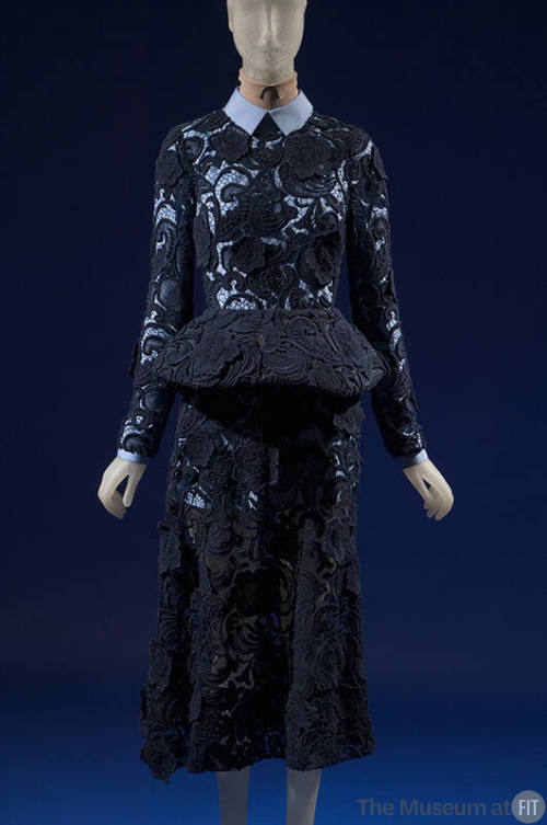 Dark blue lace dress with long sleeves, peplum and below-the-knee skirt over a blue cotton long…