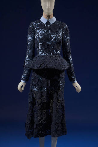 Dark blue lace dress with long sleeves, peplum and below-the-knee skirt over a blue cotton long…