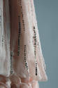 Detail view of pink evening cape showing silver vertical lines of sequins on pleats