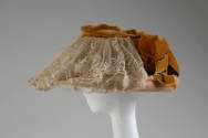 Alternate view of peach straw basket hat showing gathered ivory lace panel over front brim and …