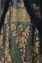 Detail view of aqua dress showing intricate cream floral embroidery and layer of black fringe t…