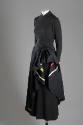 ¾ view of black long sleeve evening dress with asymmetrical overskirt draped at hip to show ivo…
