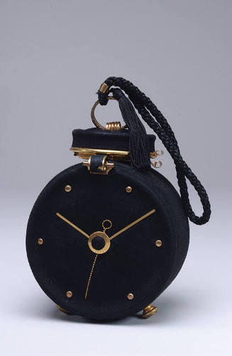 Bag in the shape of a black alarm clock with brass metal hands, dial and top trim with braided …