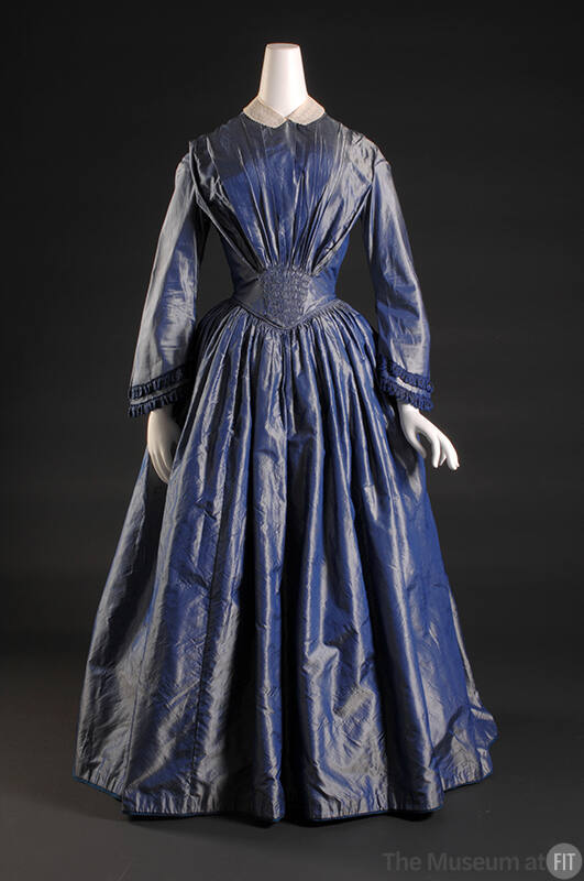 Iridescent blue silk floor length dress with long bell sleeves and pleating of bodice and of fu…