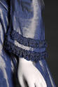 Detail view of blue dress showing bell sleeve trimmed with two rows of dark blue ribbon embroid…