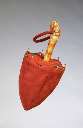 Red suede bag in the shape of a closed umbrella with gold ribs and bamboo handle with red suede…
