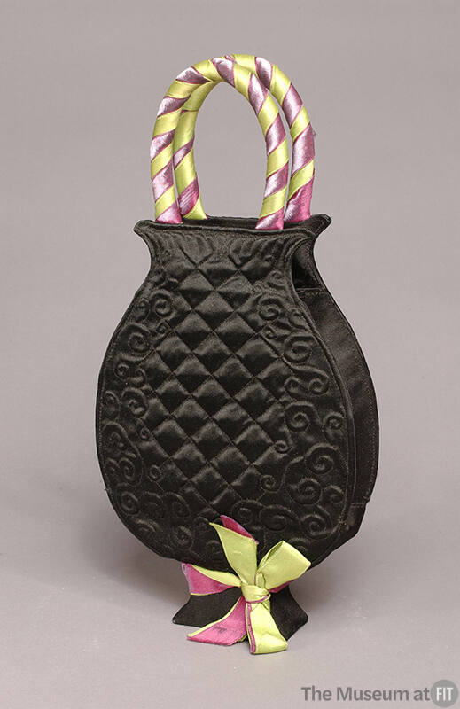 Black quilted silk bag in the shape of a vase with purple and green ribbon bow on foot and wrap…
