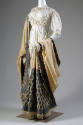 Short white jacket and matching floor length skirt trimmed with rows of puffs and off-white sha…