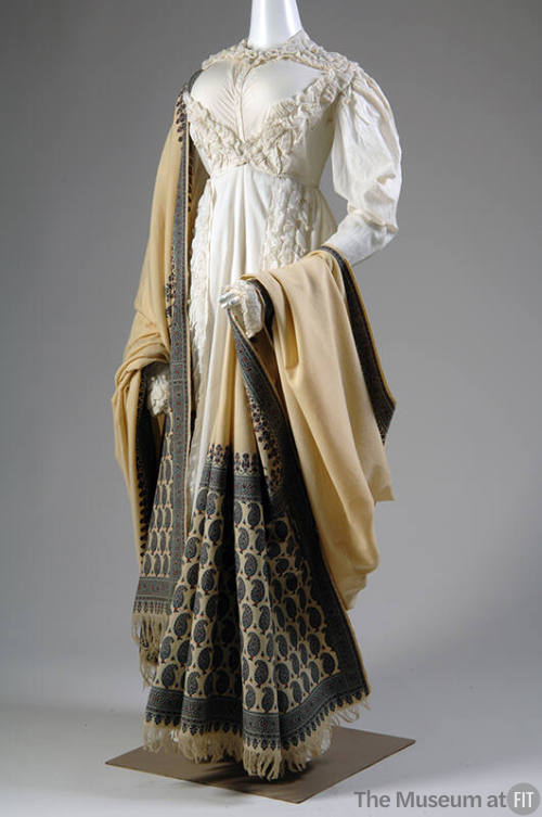 Short white jacket and matching floor length skirt trimmed with rows of puffs and off-white sha…