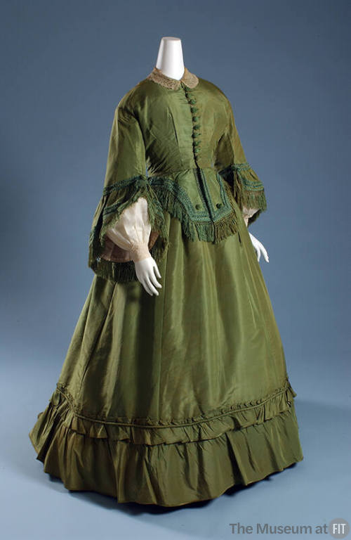 Green silk two-piece floor length dress of button front bodice with long bell sleeves, peplum a…