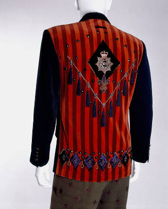 Back view of man’s red and dark red vertical striped jacket with blue sleeves, blue tassels in …
