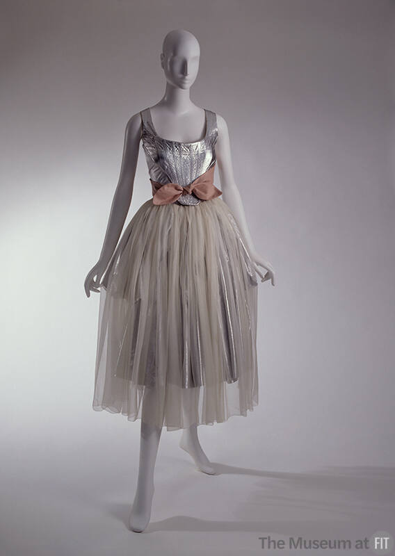 Two-piece dress of silver leather corset top and pink sash tied around waist with calf length s…