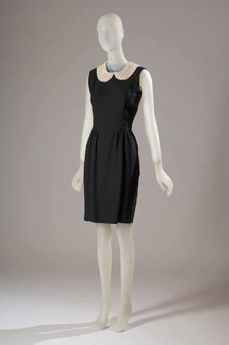 Black sleeveless knee length sheath dress with Peter Pan collar in faux pearls and pleated at s…