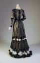 Back view of black lace long sleeve floor-length dress with high off-white lace collar, velvet …