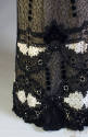 Detail of black lace dress skirt hem with black velvet rosettes and trim and off-white lace ins…