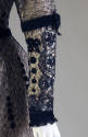 Detail of beaded dress sleeve with black net over off-white lace and velvet trim 
