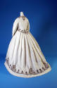 Back view of white cotton long sleeve jacket and full skirt with brown scrollwork corded border…
