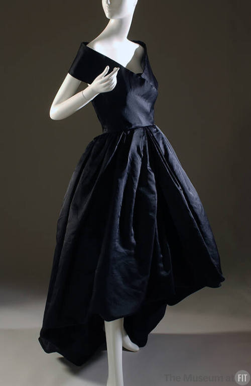 Black satin sleeveless evening dress with pleated full skirt with asymmetric hemline