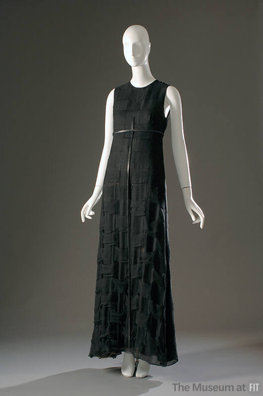 Long sleeveless black evening dress with narrow black belt with long vertical strap