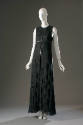 Long sleeveless black evening dress with narrow black belt with long vertical strap