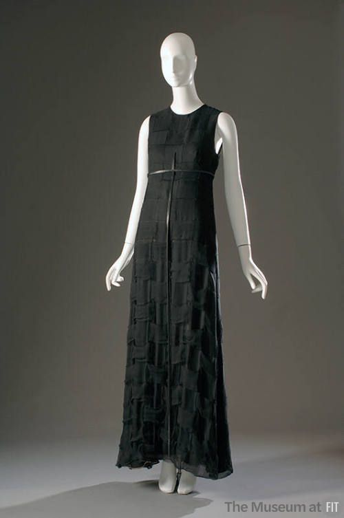 Long sleeveless black evening dress with narrow black belt with long vertical strap