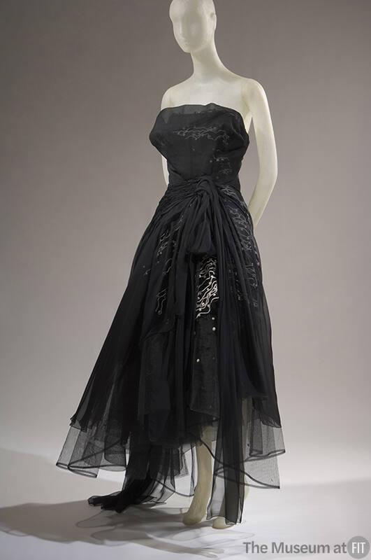 Black strapless evening dress with sheer over layer gathered at waist over white sqiggle design…