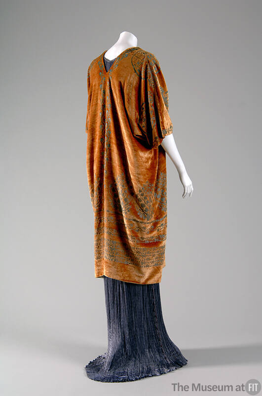 Back view of floor length light purple pleated dress with gold patterned short sleeved wrap 