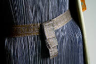 Detail of light purple pleated dress with patterned belt at waist